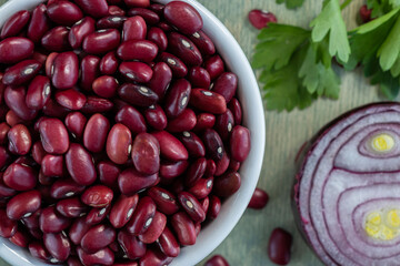 red beans in white plate with onion and parsley. close up red beans with spices on a green wooden background. Flat lay.