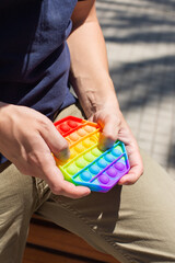 Man with rainbow anti stress pop it toy, outdoors