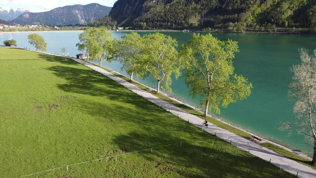 Biking next to beautiful Achen lake surrounded by astonishing mountains. The biggest lake in Tyrol, Austria. Bike lane in heart of Alps.