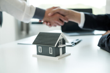 Businessmen and brokers' real estate agents shake hands after completing negotiations to buy houses insurance and sign contracts. Home insurance concept