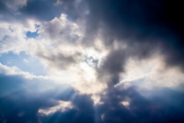 Naklejka na ściany i meble the sun's rays make their way through large dark clouds