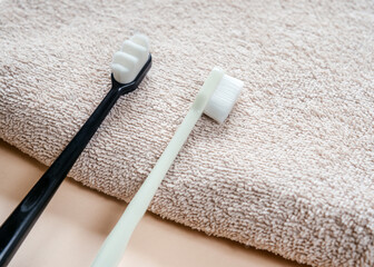 Ultra-fine toothbrushes with soft bristles on a bath towel top view, dental care and hygiene trends