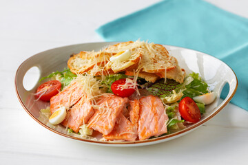 Caesar salad with grilled chicken on white wooden background