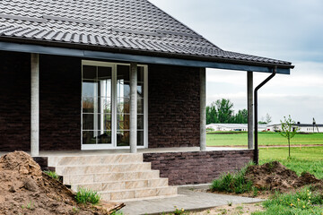 Terrace from dark decorative torn bricks in the countryside with sliding widows.