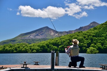 Fototapeta na wymiar 初夏の湖で釣りを楽しむ男性 