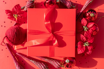 red Christmas gift box with poinsettia and ornaments on a red background