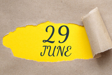 june 29. 29th day of the month, calendar date.Hole in paper with edges torn off. Yellow background is visible through ragged hole.Summer month, day of the year concept
