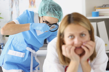 Doctor examining woman rectum with magnifying glass in clinic