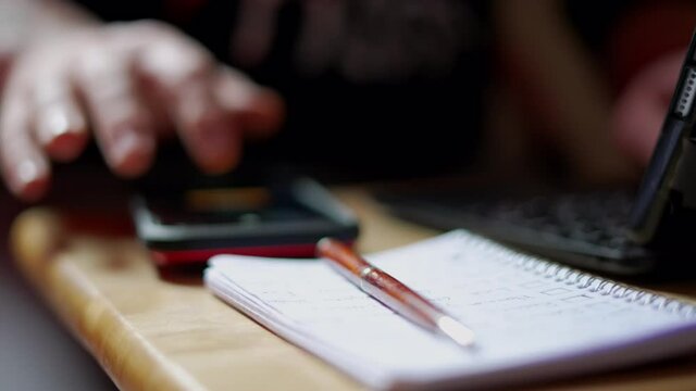 Caucasian white man with tattooed arm distracted by phone (iPhone) and ignoring ToDo list whilst working from home during Covid-19 Pandemic Quarantine. In4K 60fps real time, shot on Sony A7Siii.