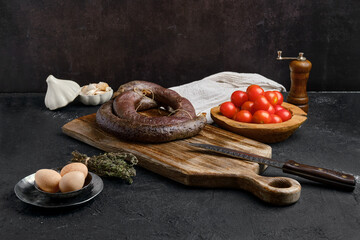 Blood sausage rolled on wooden cutting board.