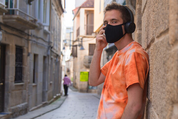 man through the monumental streets with medical mask and headphones in the new normal
