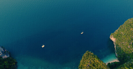 AERIAL. Top view of green island and beach with traditional thai boat at the sunset.