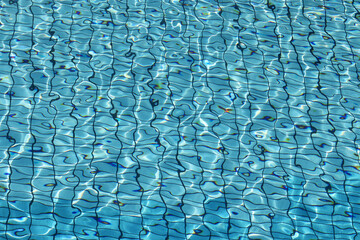 Fototapeta premium View through clean water to bottom of swimming pool lined with blue tiles