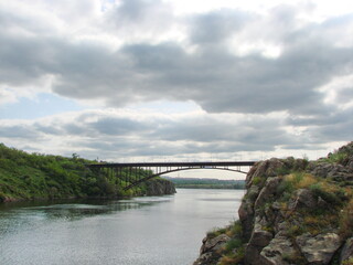 Bottom view of the power and grandeur of the arch bridge against the background of heavy gray clouds.