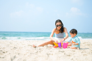 Happy family resting at beach in summer, Mother and baby feet at the sea foam at the sunlight water is moving