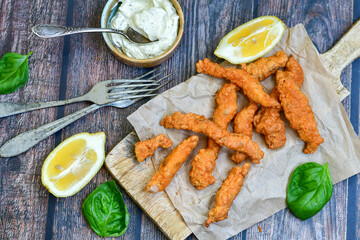 
 Crispy  deep fried home made    chicken strips Breaded  with  almond flour chicken  breast fillets  with chilly peppers and fresh   basil on wooden rustic background. Ketogenic diet food