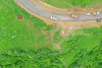 Aerial top view sharp turns in green mountains.  Winding mountain road.  Construction works on highway.