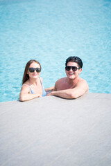 Man and woman in a swimming pool. Young couple embracing in the pool. couple looking at the camera.