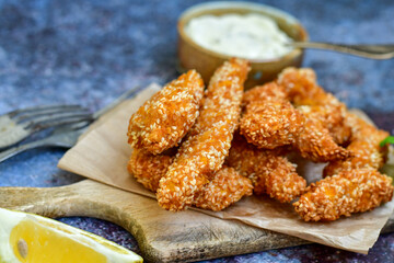 
 Crispy  deep fried   chicken strips  with sesame seeds and french fries . Breaded  with cornflakes chicken  breast fillets  with chilly peppers and fresh   basil on wooden rustic background