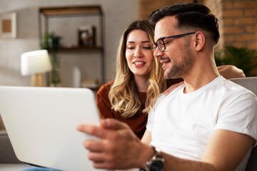 Happy young couple with laptop at home. Boyfriend and girlfriend watching movie on laptop.