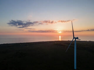 Wind turbines on sunset against sun with sea on background, Estonia.Renewable energy