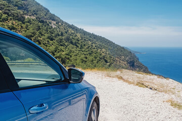 Blue car stopped roadside near the sea on sunny day