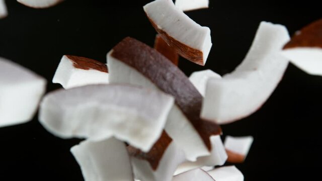 Super slow motion of falling pieces of coconut, isolated on black background. 1000 fps.