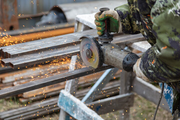 Fototapeta na wymiar A worker cuts metal at a construction site.