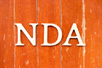 Alphabet letter in word NDA (Abbreviation of Non disclosure agreement) on old red color wood plate...
