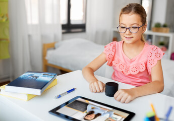 online education, e-learning and technology concept - student girl in glasses with smart speaker and teacher on tablet computer screen having video class at home