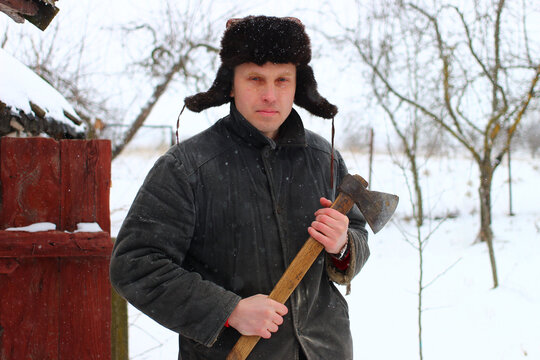 Poor young peasant in winter with an ax
