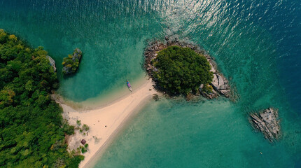 AERIAL. Top view of green island and beach with traditional thai boat at the sunset.