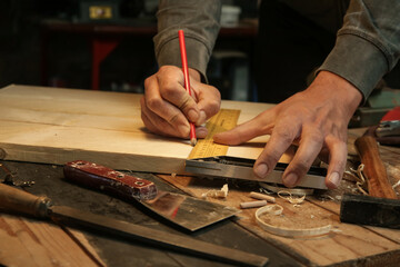 Carpenter measuring and marking wood with speed square measure tool in workshop	