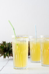 Delicious sweet refreshing pineapple juice with ice in glasses with a straw
