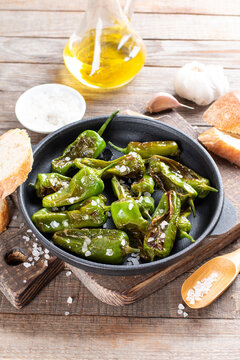 Grilled pepper Padron in a frying pan on a table. Spanish cuisine. Pimientos de Padron