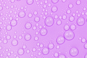 Water drops on purple background texture. Backdrop glass covered with drops of water.  violet bubbles in water