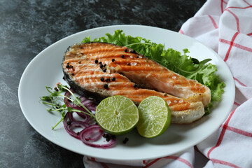 Concept of tasty eating with grilled salmon on black smokey background