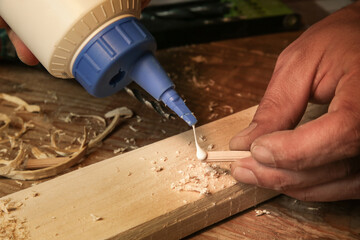 Handyman assembling wooden pieces with a glue - obrazy, fototapety, plakaty