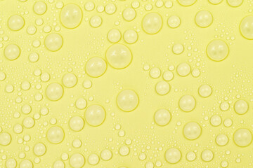 Water drops on yellow background texture. Backdrop glass covered with drops of water. yellow bubbles in water. beer texture