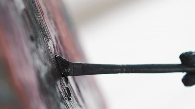 Skilled artist draws picture applying dark paint with paintbrush on canvas at art lesson in studio extreme closeup slow motion vertical shot
