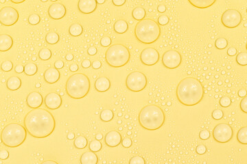 Water drops on yellow background texture. Backdrop glass covered with drops of water. yellow bubbles in water. beer texture