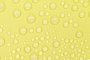 Water drops on yellow background texture. Backdrop glass covered with drops of water. yellow bubbles in water. beer texture