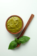 Bowl of Pesto sauce, basil and spoon on white background