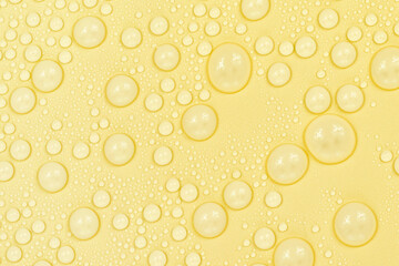 Water drops on yellow background texture. Backdrop glass covered with drops of water. yellow bubbles in water. beer texture