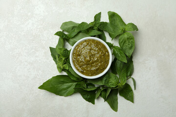 Bowl of Pesto sauce and basil on white textured background