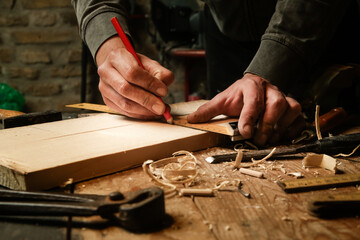 Carpenter measuring and marking wood in workshop