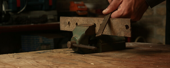 Man working with a piece of iron in mini table clamp