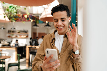 Smiling young hispanic man in earphones on a video call