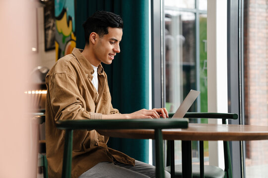 Young Hispanic Man Student Sitting At The Cafe Table Indoors