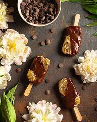chocolate popsicle with edible gold on a stick on a dark background. Round pieces of chocolate. Top view. Chocolate ice cream made from dark bitter, milk chocolate